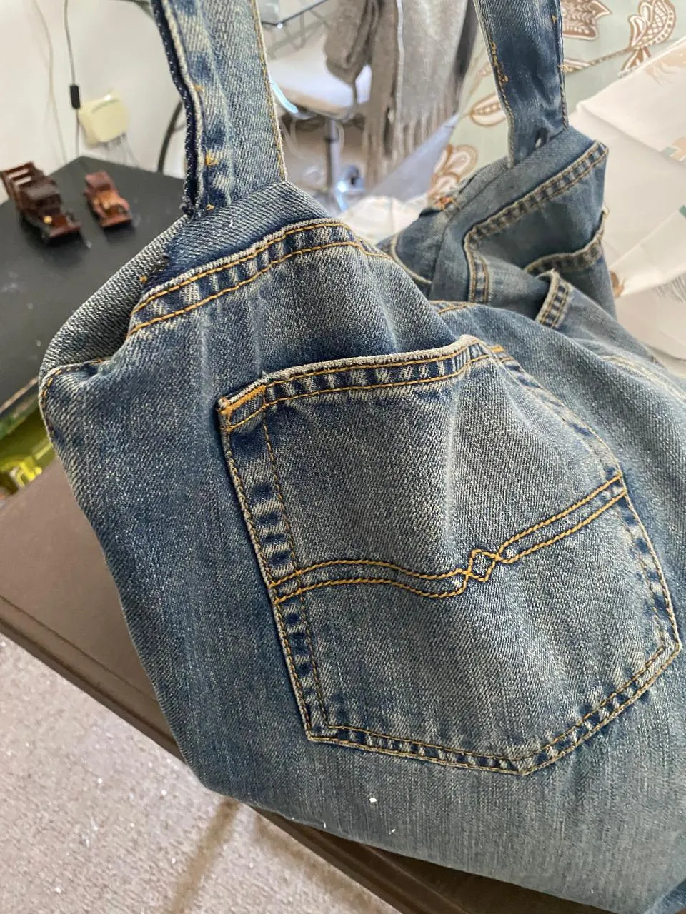 Cojín de jeans reutilizado con bolsillo trasero, costuras doradas y asas